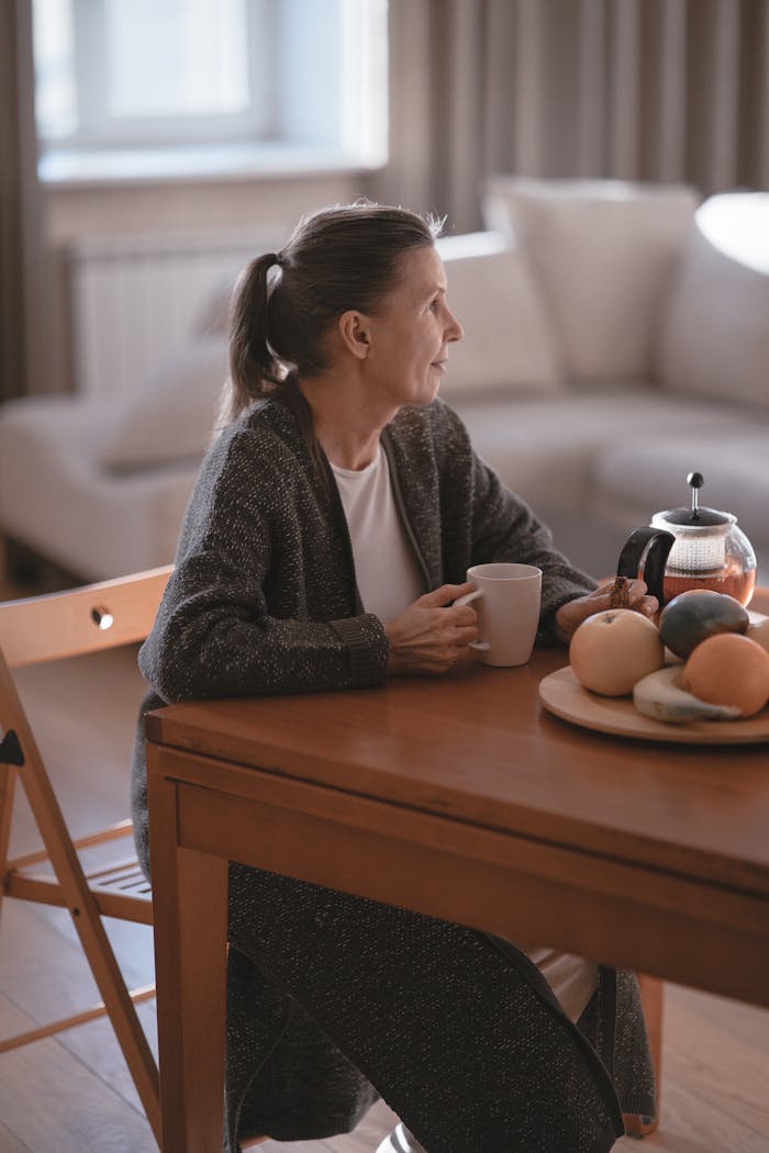 Senior woman enjoying coffee in a cozy home setting, reflecting a peaceful and relaxed moment of leisure.